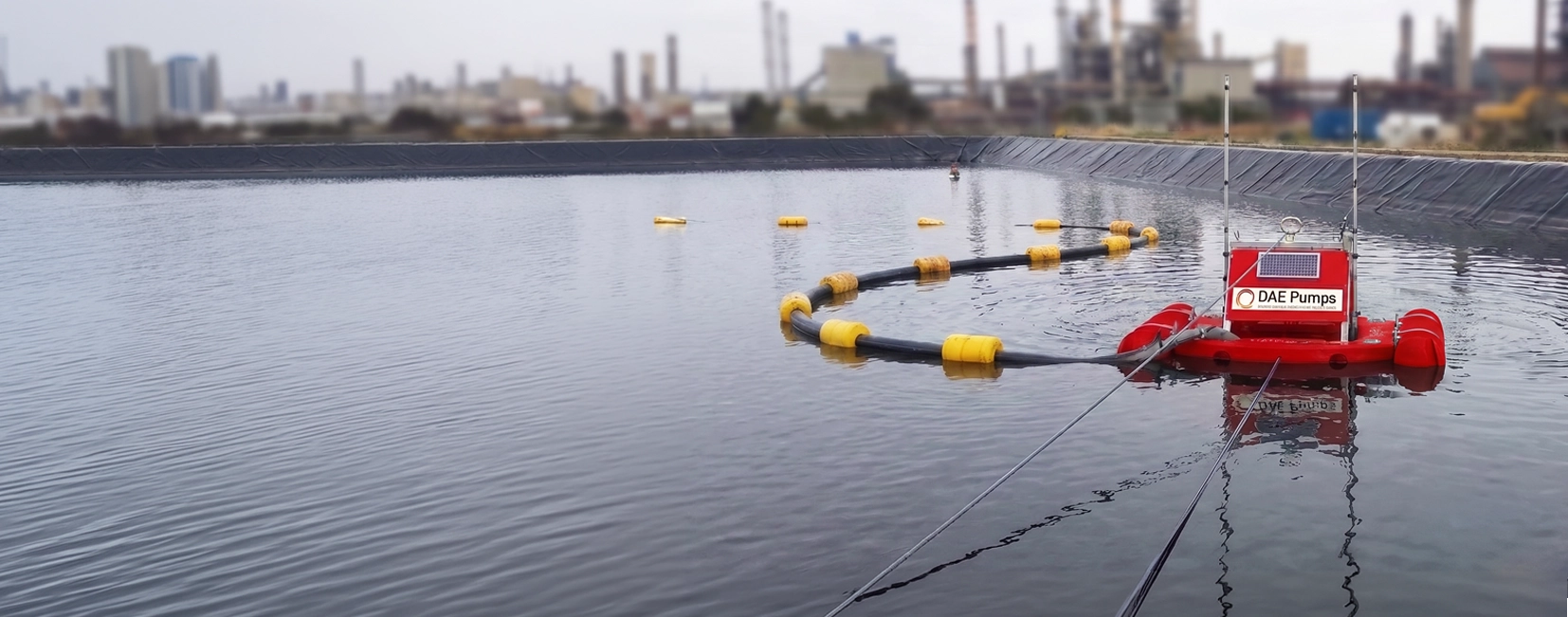 DAE Pumps pontoon mini dredge working in a lined industrial pond with a floating discharge line