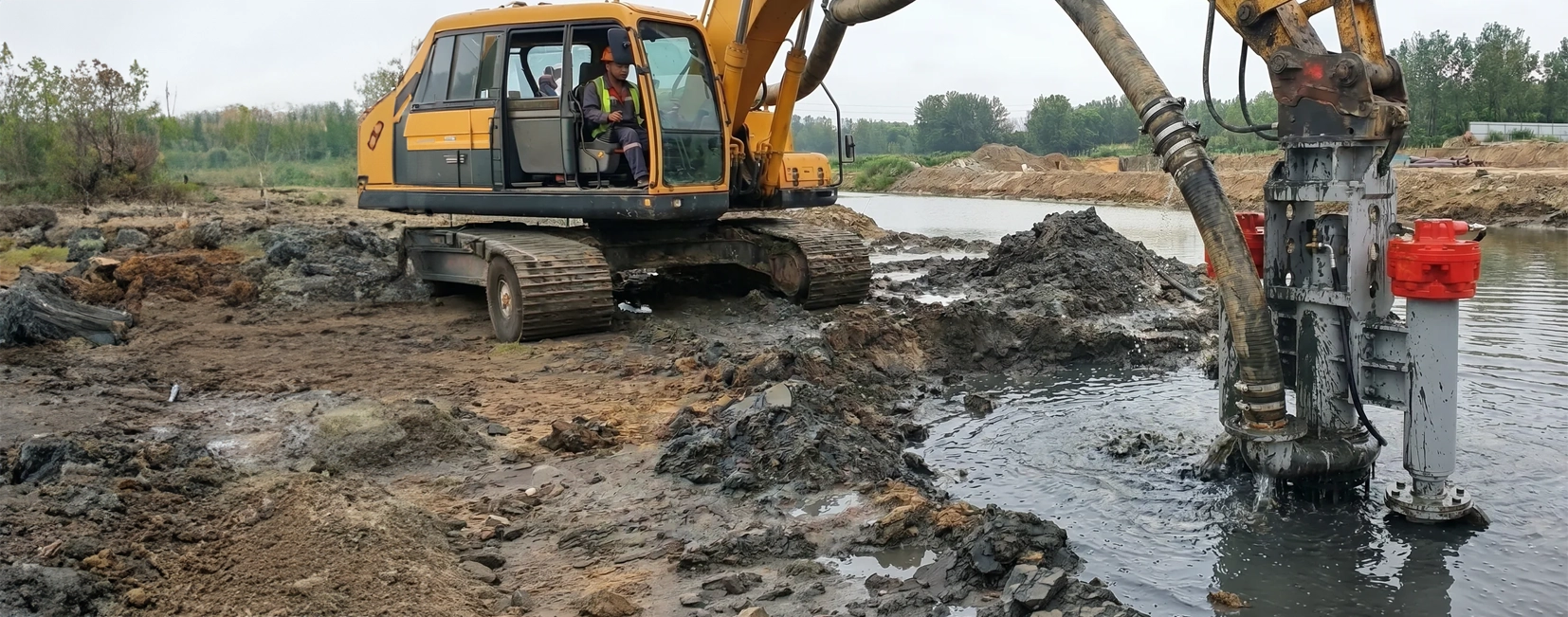 Excavator-Mounted Dredge Pump at Work Excavator lowering a DAE Pumps hydraulic dredge pump into a muddy pond to remove sediment