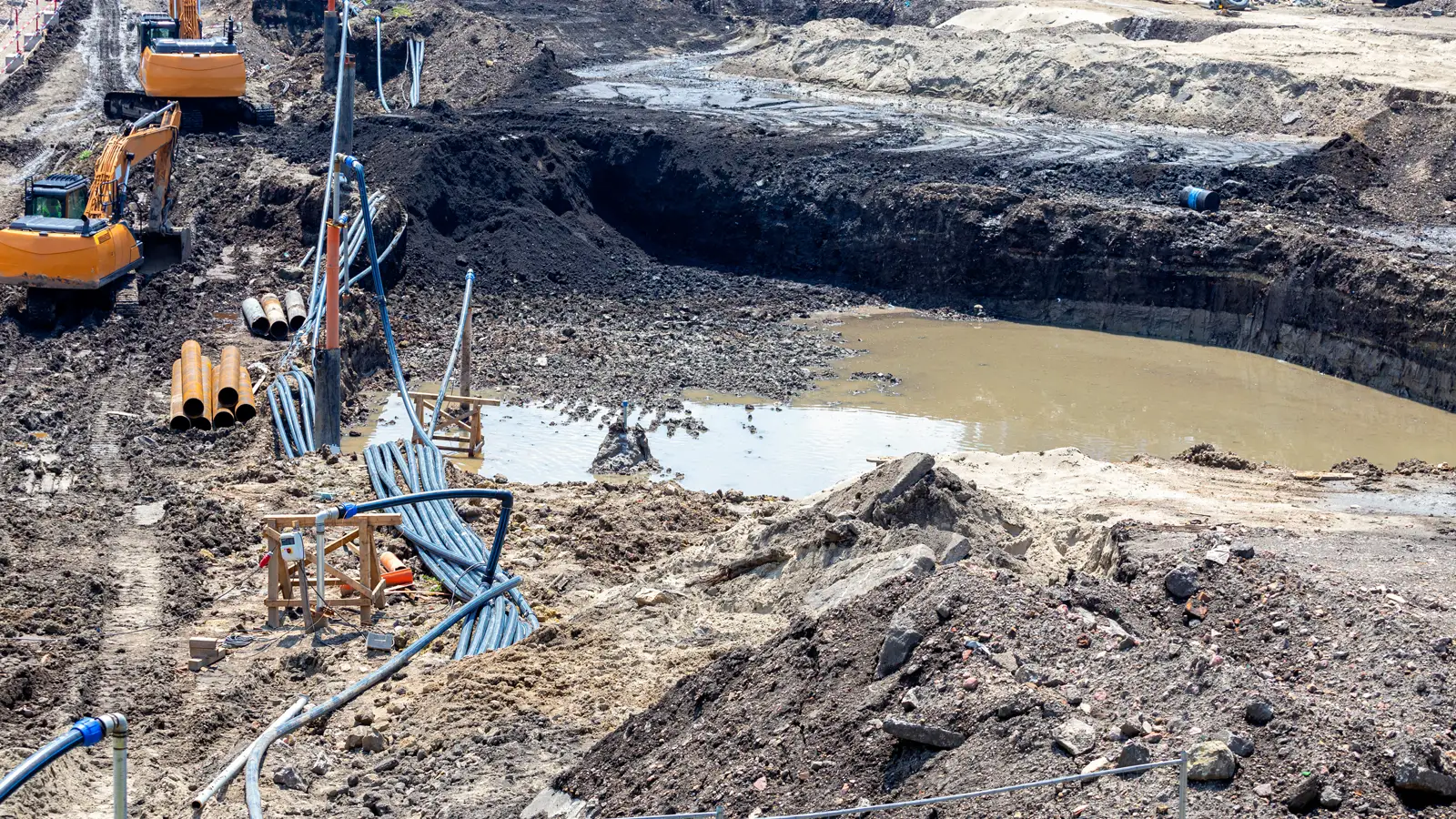 Construction and Site Dewatering Construction excavation being dewatered with hoses and wellpoint pipes beside excavators