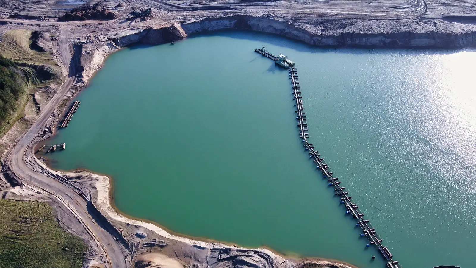 Mining and Quarry Dewatering Aerial view of a flooded quarry pit with a floating pipeline across the water